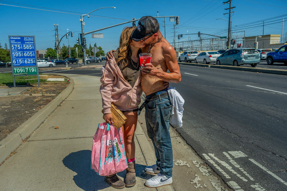 Califia Carlisle and her boyfriend, Justin Hartung kiss as she takes a break from asking motorists for money at the intersection of Howe Avenue and Folsom Boulevard in Sacramento in July. Hartung says “it’s a hard life” living on the street and stays close to Carlisle to protect her.
